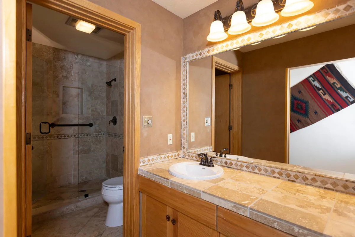 A clean, well-lit laundry facility featuring a sink, shower stall, and mirror. The space is practical and inviting, perfect for self-care and everyday convenience during extended stays.